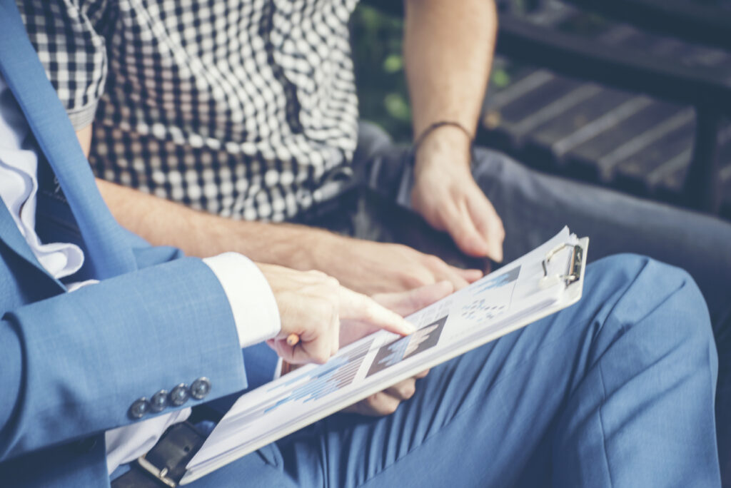 two guys looking at data analytics report on clipboard